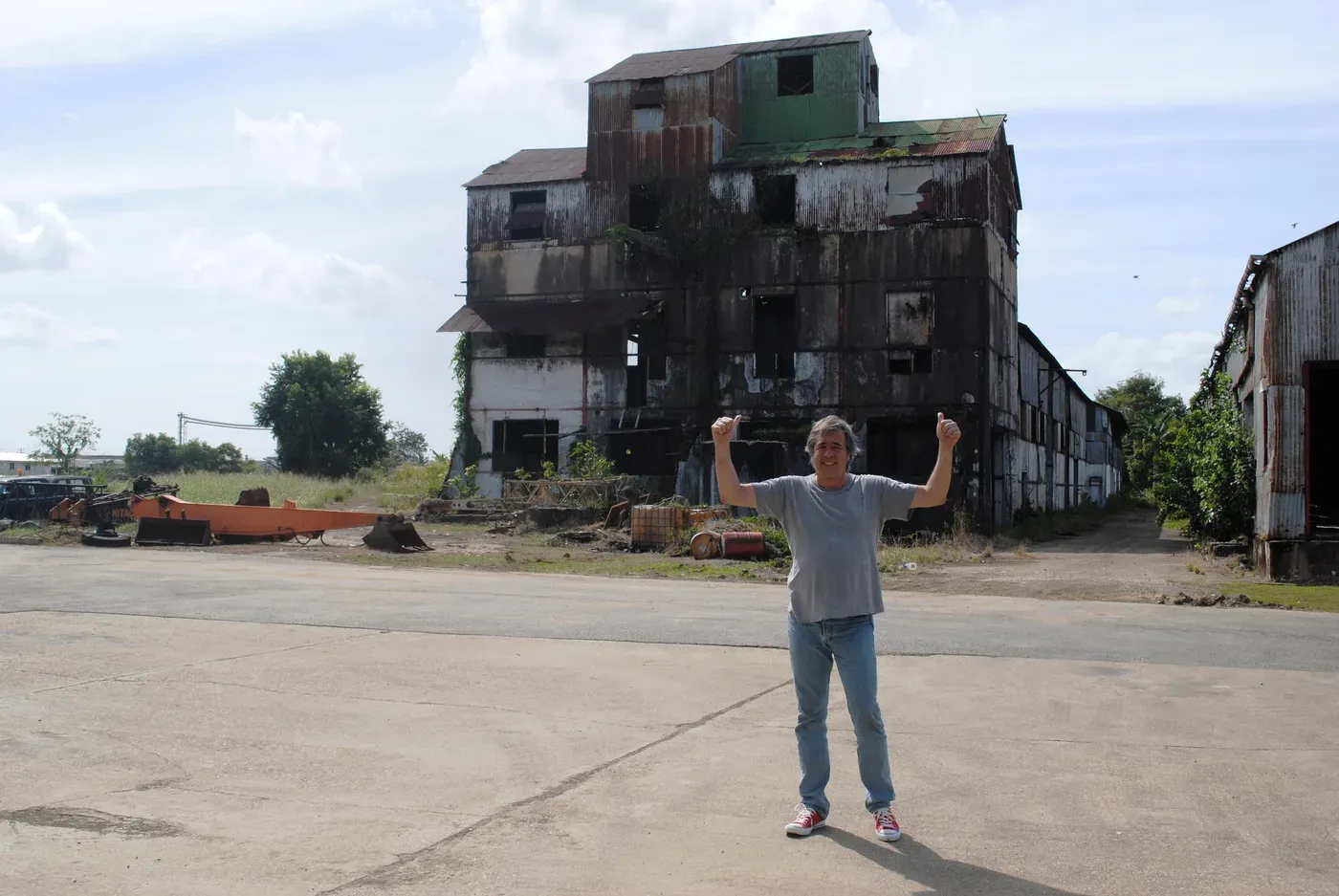 Luca Gargano, arms raised, in front of the ruined Caroni distillery building